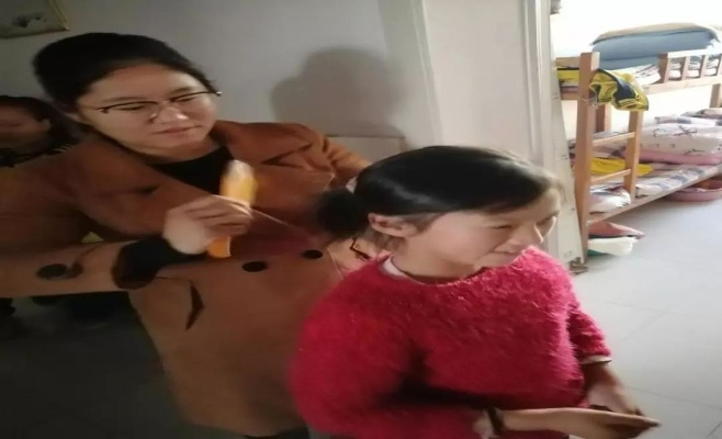 老师帮学生把头发梳成大人模样，用爱与智慧引领成长